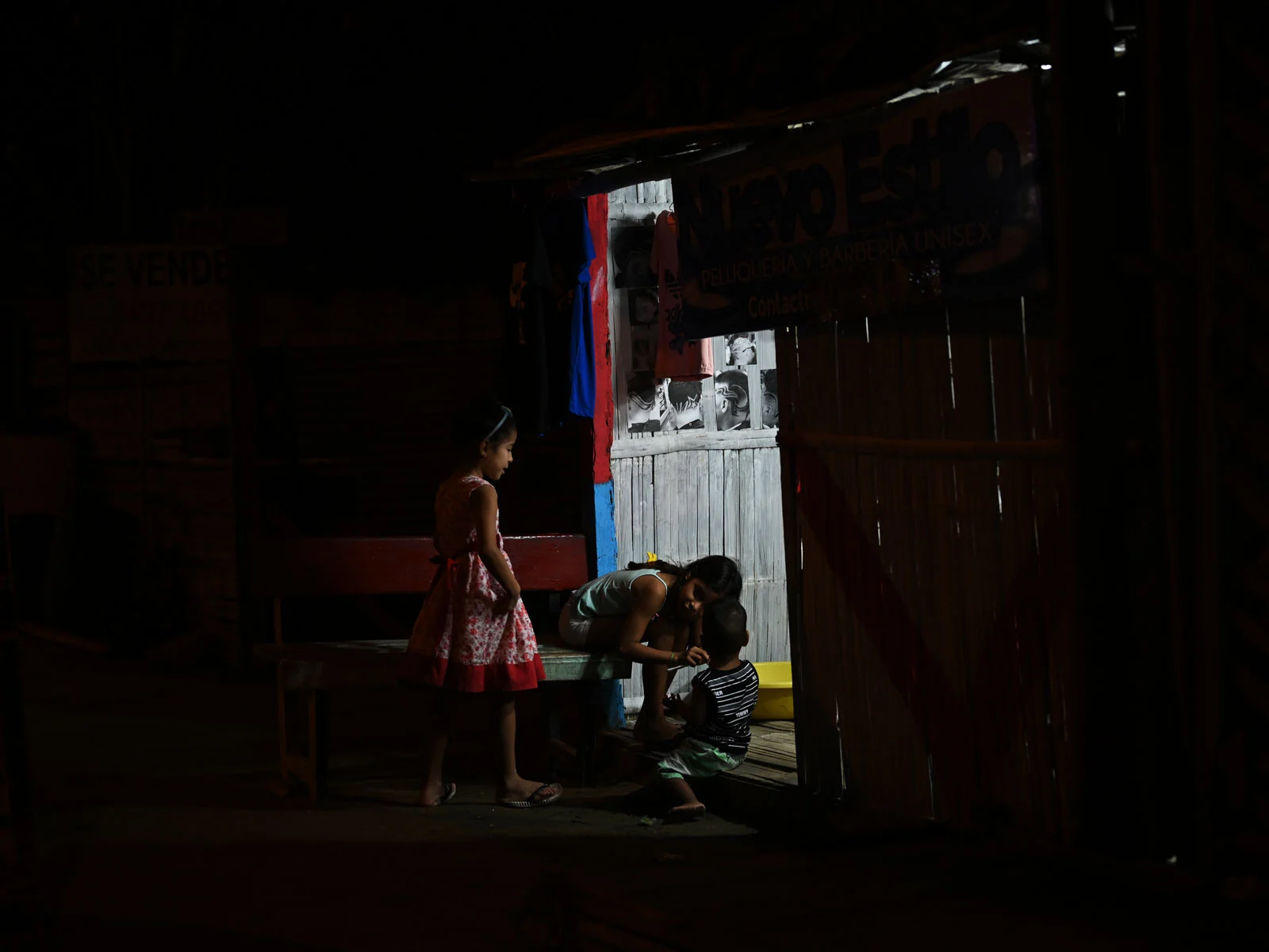 Sister about 8 to 14 years in a dark setting. Playing at the front door. Lit up by the light inside.